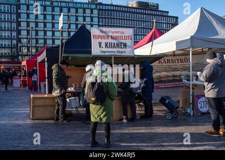 Persone, bancarelle del mercato e tendoni in una soleggiata giornata invernale a Hakaniemen Maalaismarkkinat sulla piazza del mercato di Hakaniemi a Helsinki, Finlandia Foto Stock