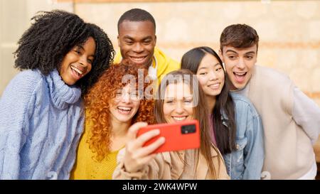 Adolescenti diversi che si fanno un selfie sorridendo e ridendo all'aperto Foto Stock
