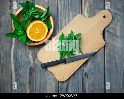 Agrumi e menta su un tagliere. Fresca limonata estiva di agrumi con lime, menta, arance e cubetti di ghiaccio su fondo in legno. Fare riferimento Foto Stock