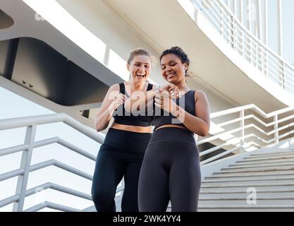 Due donne più grandi che guardano lo smartwatch mentre scendono sulle scale Foto Stock