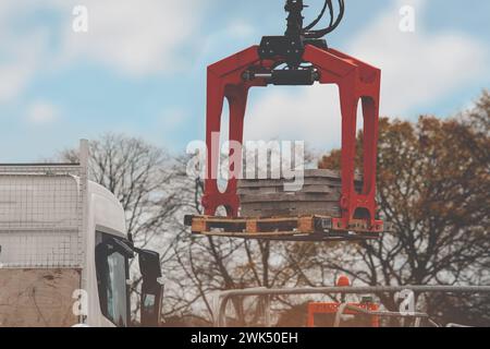 Materiali da costruzione consegnati in loco e scaricati da una gru montata su autocarro idraulico Foto Stock