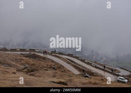 Srinagar, Kashmir, India. 18 febbraio 2024. I residenti camminano lungo la strada durante la pioggia alla periferia di Srinagar, la capitale estiva di Jammu e Kashmir. Sono state segnalate nevicate fresche nei tratti più alti del Kashmir, mentre le pianure hanno subito piogge, con un conseguente calo significativo delle temperature.l'ufficio meteorologico ha previsto nevicate da moderata a pesante o precipitazioni attraverso la valle del Kashmir per i prossimi tre giorni. (Immagine di credito: © Saqib Majeed/SOPA Images via ZUMA Press Wire) SOLO PER USO EDITORIALE! Non per USO commerciale! Foto Stock