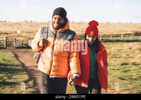 Ritratto di una coppia felice innamorata che cammina lungo la campagna al tramonto. Amore, escursionismo e stile di vita attivo immagine tonificata Foto Stock