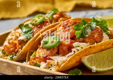 Deliziosi tacos di gamberi su vassoio di legno con fette di lime Foto Stock