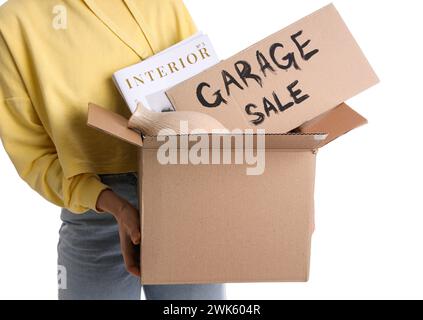 Donna che tiene in mano una scatola di oggetti indesiderati e un cartone con VENDITA IN GARAGE DI testo su sfondo bianco Foto Stock