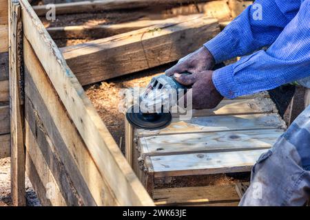 falegname afroamericano che crea una casa wendy, capannone di legno all'aperto, da vicino, sta macinando le tavole e assemblarle in pannelli Foto Stock