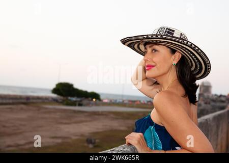 Bella donna che indossa il tradizionale cappello colombiano chiamato Sombrero Vueltiao alle mura storiche di Cartagena de Indias Foto Stock