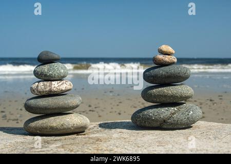 Rock cairns sulla spiaggia con onde in lontananza Foto Stock