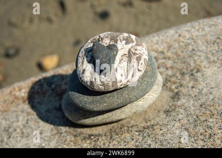 Roccia a forma di cuore su cairn in spiaggia Foto Stock