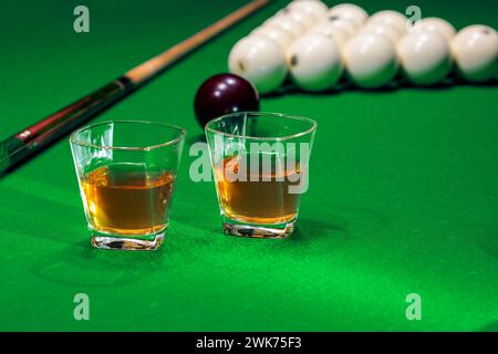 Due bicchieri di whiskey sul tavolo da biliardo con spilli e palline da biliardo sullo sfondo Foto Stock