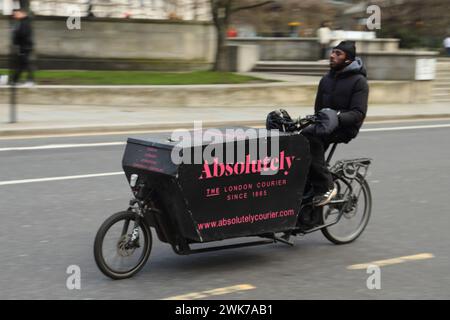 Un corriere assolutamente ciclistico in sella a una bici e-cargo, Londra, Regno Unito Foto Stock