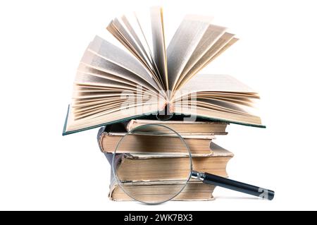 Pile di vecchi libri e lenti d'ingrandimento isolate su sfondo bianco Foto Stock