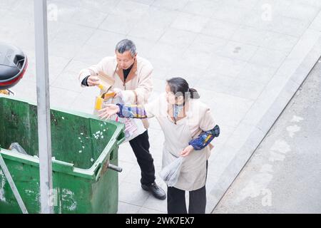 Vecchio e donna che portano fuori spazzatura Foto Stock