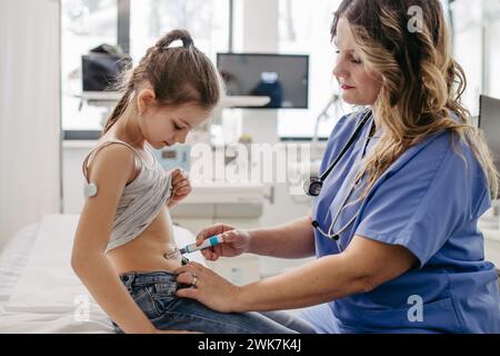 Infermiera iniettando insulina nella pancia della giovane ragazza diabetica. Primo piano di una ragazza con diabete di tipo 1 che prende insuling con l'ago della siringa. Foto Stock