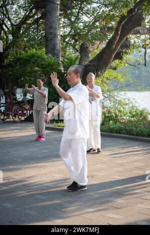 Gente che fa tai chi di mattina presto intorno al lago Hoan Kiem ad Hanoi, Vietnam Foto Stock