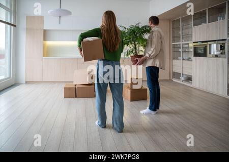 Nuovi proprietari di case con scatole e impianti domestici in mano. Trasferimento di riscaldamento domestico in un appartamento di mutui. Foto Stock