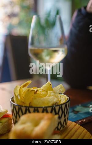 Una persona è seduta a un tavolo con un bicchiere di spumante prosecco di fronte a loro. Sembra che stiano godendo un momento di relax, assaporando Foto Stock