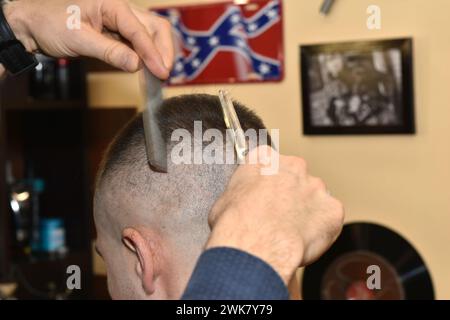 La foto cattura il momento in cui un parrucchiere taglia la testa di un cliente. Foto Stock