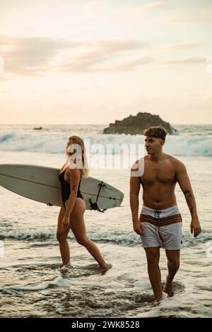 Coppia che fa surf su una bella spiaggia di Tenerife durante il tramonto Foto Stock