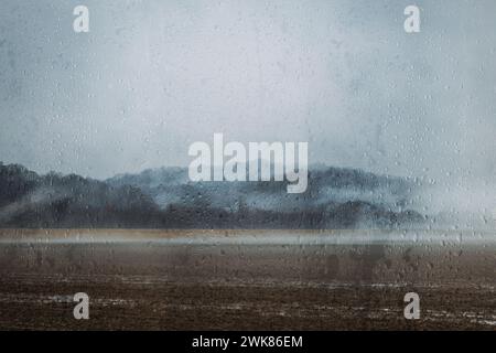 Paesaggio cupo attraverso le gocce di pioggia sulla finestra il giorno della pioggia Foto Stock