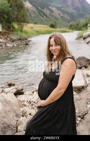 donna che tiene in mano la pancia durante il servizio fotografico di maternità Foto Stock