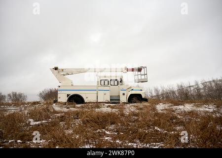 Gru a sollevamento braccio parcheggiata su un campo di erba asciutta e innevata Foto Stock