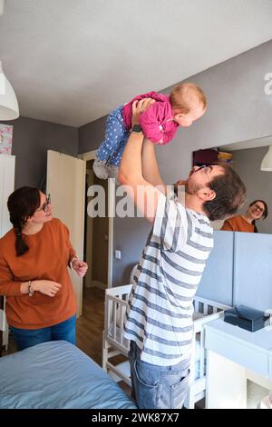 Genitori felici che giocano con la loro bambina di 6 mesi a casa. Foto Stock