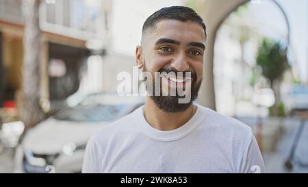Bell'uomo barbuto sorridente all'aperto in una città, raffigurante lo stile di vita urbano e la positività. Foto Stock