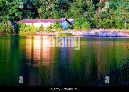 Una struttura rurale sul lungolago circondata da lussureggianti alberi verdi Foto Stock