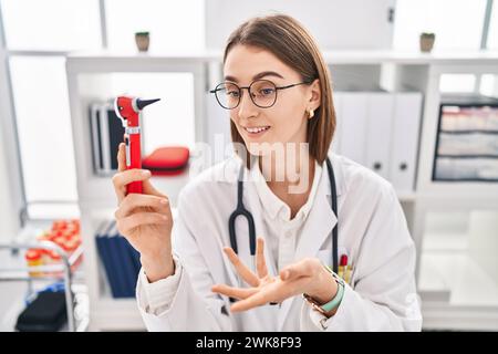 Giovane donna caucasica medico con otoscopio in clinica Foto Stock