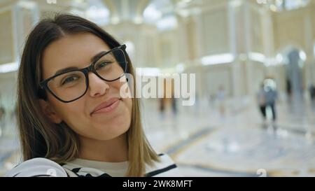 Donna bruna sorridente con occhiali all'interno del lussuoso qasr al watan di abu dhabi Foto Stock