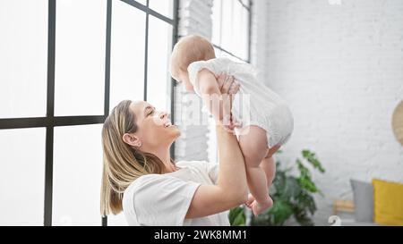 Madre che tiene una figlia in volo in piedi a casa Foto Stock