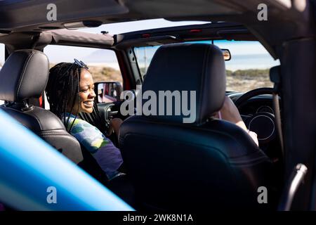 La giovane donna afroamericana si diverte a fare un giro in auto durante un viaggio in auto Foto Stock