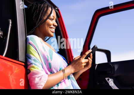 Una donna afro-americana gioiosa ama fare una chiacchierata durante un viaggio. Foto Stock