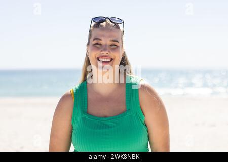 Una giovane donna caucasica di grandi dimensioni sorride brillantemente in spiaggia Foto Stock