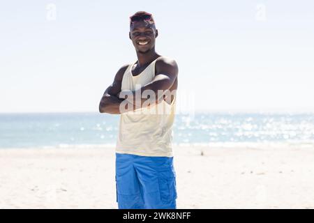 Il giovane afroamericano sta in piedi con fiducia sulla spiaggia Foto Stock