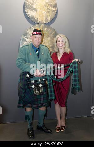 Parigi, Francia. 17 febbraio 2024. Un suonatore di cornamuse e pittrice Adelaide Leferme posa accanto al suo lavoro durante il Salon 2024, CAPITALE DELL'ARTE Foto Stock