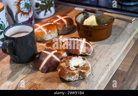 Panini Hot Cross tostati con burro, un piatto tradizionale da colazione consumato a Pasqua Foto Stock