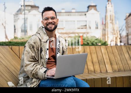 Il giovane uomo hipster di affari freelance sta lavorando a un nuovo progetto all'esterno su un computer portatile. Uomo d'affari che lavora e lavora in telelavoro all'aperto all'aria aperta Foto Stock