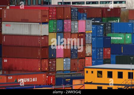 Città dei container - un'alta pila di container per spedizioni multiple sminuisce un edificio giallo di uffici a tre piani sulla banchina di Southampton, aprile 2023. Foto Stock