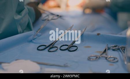 Primo piano di più strumenti chirurgici sul tavolo in sala operatoria i chirurghi del team medico eseguono operazioni mediche utilizzando bisturi pinzette forbici chirurgiche Foto Stock