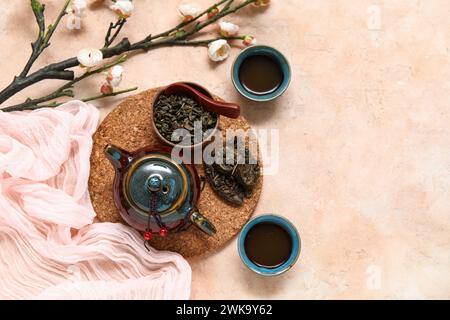 Composizione con teiera e tazze in ceramica di puer tea aromatico su sfondo beige Foto Stock