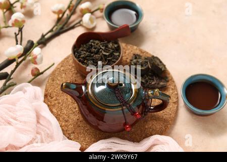 Composizione con teiera e tazze in ceramica di puer tea aromatico su sfondo beige Foto Stock