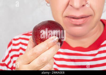 La donna, il cui volto non è visibile, tiene in mano una mela rossa. Foto Stock