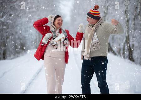 Una coppia anziana nella natura invernale con i pattini andrà alla pista di pattinaggio, ridendo e divertendosi. Buone vacanze invernali ai pensionati. Foto Stock