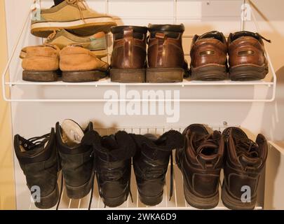 Stivali e scarpe in pelle scamosciata e in pelle ben assortiti su portascarpe per uso domestico. Foto Stock