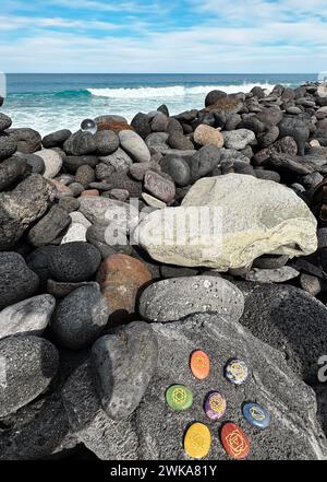 Cristalli curativi, pietre chakra. Pietre arcobaleno in un cerchio sulla costa grigia dell'oceano vulcanico Foto Stock