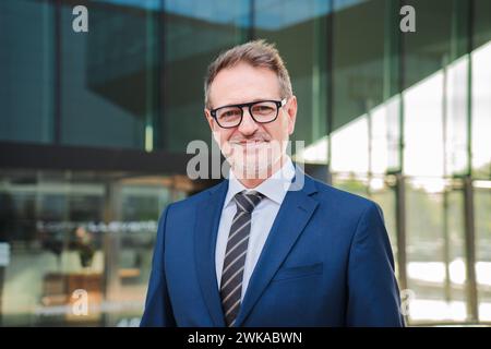 Ritratto individuale di un bell'uomo d'affari che sorride e guarda la fotocamera che indossa una tuta blu formale sul posto di lavoro. Un vero e proprio uomo esecutivo o ceo di successo che guarda in prima linea. uomo d'affari degli anni '50. Foto di alta qualità Foto Stock
