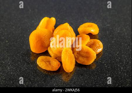 Una vista ravvicinata delle albicocche secche in un piolo su un piatto di marmo scuro Foto Stock