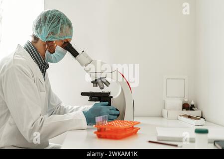 Scienziato della ricerca biochimica che lavora con il microscopio nella ricerca farmaceutica in laboratorio Foto Stock